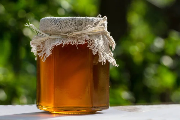 Jar with honey on table against nature background 스톡 이미지