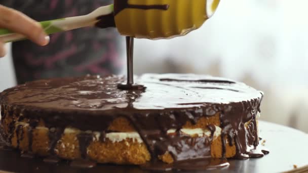 Mano femminile versare la crema di cioccolato sulla torta e iniziare a diffondersi . — Video Stock