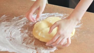 Kadın elleri masada un içinde hamur yoğuruyor.