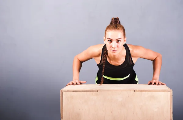 Beautiful sports woman doing push ups on fit box at gym