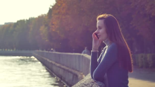 Attraktiv ung kvinna njuter av solskenet i parken när hon pratar i telefon. — Stockvideo