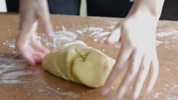 Женские руки месят тесто в муке на столе — стоковое видео