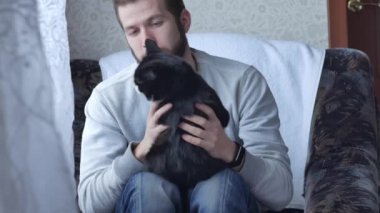 Onun siyah kedi ile oynarken sakallı bir genç adam