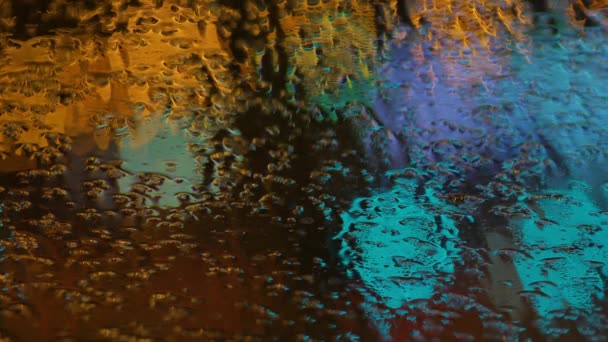 Fundo desfocado. Movendo círculos bokeh de tráfego noturno. semáforos noturnos desfocados Através do vidro em gotas de chuva. Colorido, borrado, bokeh luzes fundo . — Vídeo de Stock