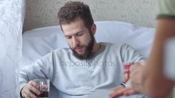 Двое друзей-мужчин разговаривают и пьют чай или кофе на диване дома — стоковое видео