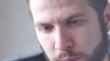 Bir beyaz genç esmer kıvırcık sakallı adam cep telefonu dokunmatik ekran kullanarak telefon yakın çekim eller kullanır