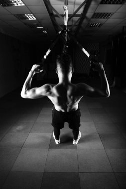 Bir genç yakışıklı cesur kıvırcık sakallı kaslı adam sakallı toplam direnç egzersizleri spor salonunda egzersiz fitness trx askıları yapar.