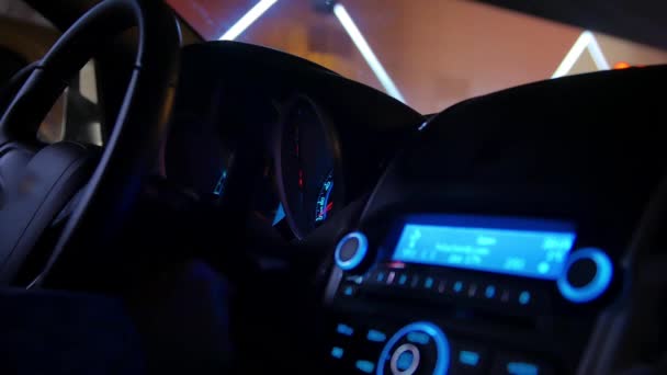 O motorista senta-se no carro à noite gira a chave da ignição começa seu motor e o painel de banho de sol da luz azul — Vídeo de Stock