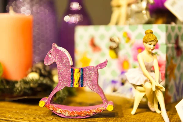 Standbeeld van zittende ballerina en paard omringd door vakken en ander speelgoed op houten tafel — Stockfoto