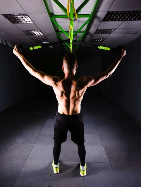 Bir genç yakışıklı cesur kıvırcık sakallı kaslı adam sakallı toplam direnç egzersizleri spor salonunda egzersiz fitness trx askıları yapar.