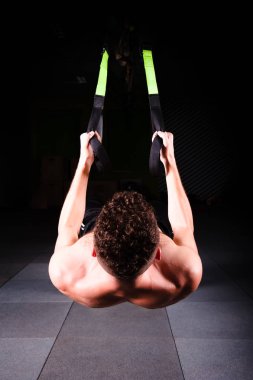 Bir genç yakışıklı cesur kıvırcık sakallı kaslı adam sakallı toplam direnç egzersizleri spor salonunda egzersiz fitness trx askıları yapar.