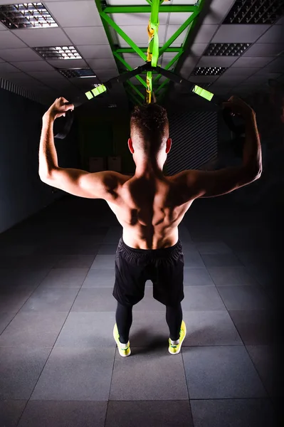 Ένα νεαρό όμορφος γενναία σγουρά γενειοφόρος μυώδης άνδρας με μούσι κάνει συνολική αντίσταση ασκήσεις ιμάντες γυμναστικής που εργάζονται έξω στο γυμναστήριο — Φωτογραφία Αρχείου