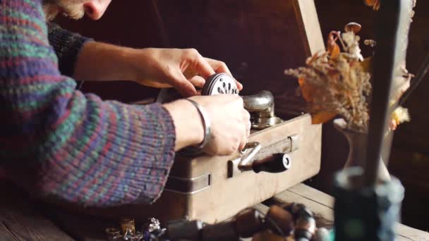 Un joven barbudo en un suéter implica jugar con un viejo gramófono — Vídeos de Stock