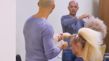 İki berber veya Kuaför Güzellik Salonu Kuaför tarafından modelinin kıvırcık saç şekillendirme yapar