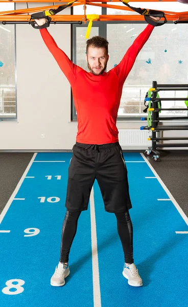 Sporty male øvelser gjør y deltoid fly med treningsstropper i gymmen – stockfoto