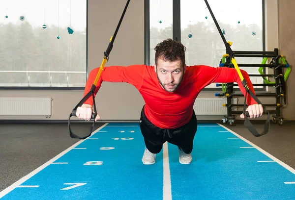 Weißer lockiger bärtiger Mann, der mit Trageschlaufen im Fitnessstudio trainiert — Stockfoto