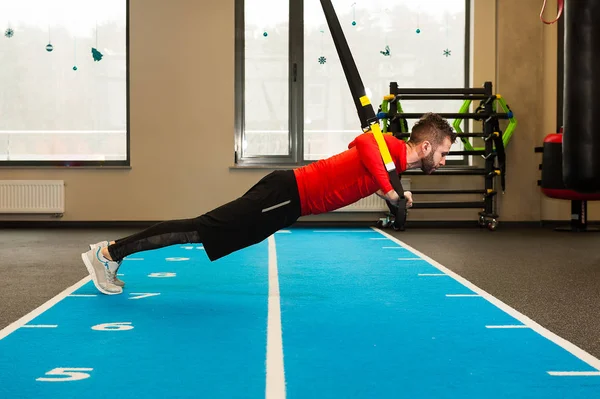 Branco encaracolado barbudo desportivo homem exercitando com trx tiras de fitness no ginásio — Fotografia de Stock