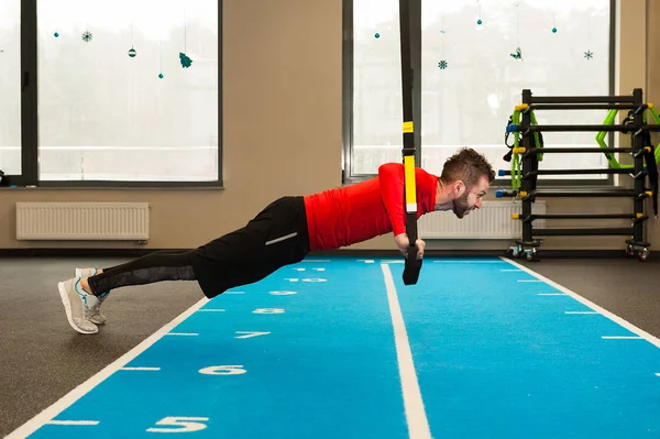 Branco encaracolado barbudo desportivo homem exercitando com trx tiras de fitness no ginásio — Fotografia de Stock