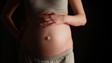 Hamile kadının karnı siyah arka plan üzerine okşama