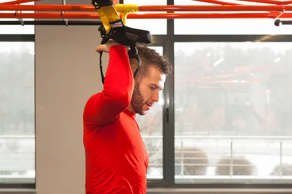 Treino TRX. Instrutor de Crossfit no ginásio fazendo TRX Excersise. Homem de fitness exercita-se nos anéis. Homem de fitness no ginásio. Estilo fitness. Treino em anéis. Desporto e fitness. Treino Crossfit — Fotografia de Stock