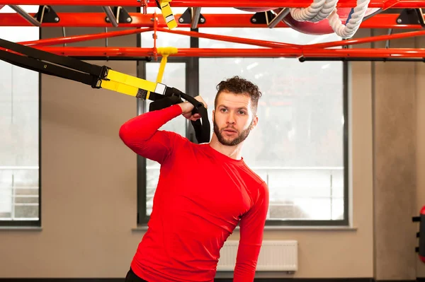 Treino TRX. Instrutor de Crossfit no ginásio fazendo TRX Excersise. Homem de fitness exercita-se nos anéis. Homem de fitness no ginásio. Estilo fitness. Treino em anéis. Desporto e fitness. Treino Crossfit — Fotografia de Stock