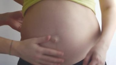 İhale eller gelecek baba. Bir pencere önünde duran hamile kadın. Güçlü erkek yavaşça konturlu yuvarlak karın eller