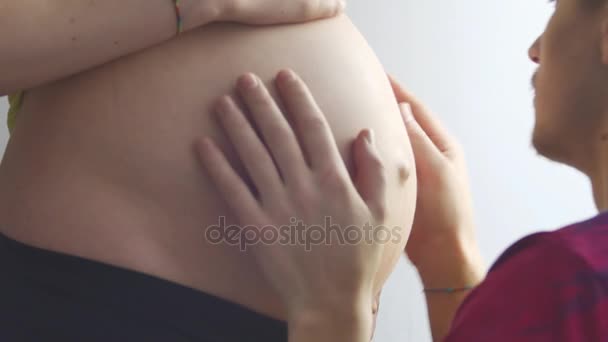 Manos Tiernas el Futuro Padre. Mujer embarazada de pie frente a una ventana. Manos masculinas fuertes acariciaron suavemente el vientre redondo — Vídeos de Stock