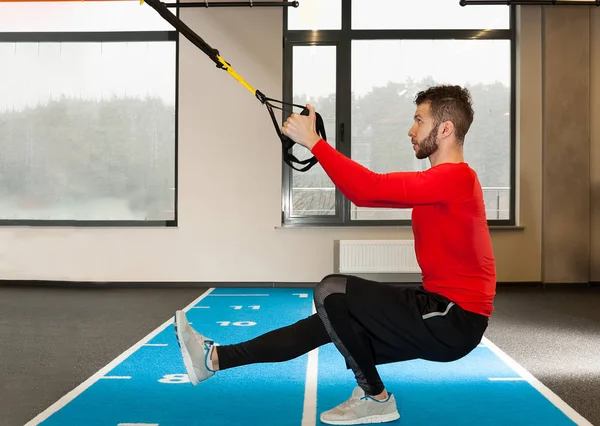 Branco encaracolado barbudo desportivo homem exercitando com alças de fitness no ginásio — Fotografia de Stock