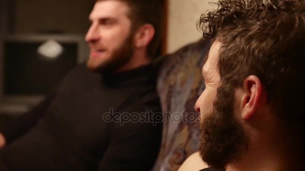 Handheld shot of bearded man telling story to surprised friend — Stock Video