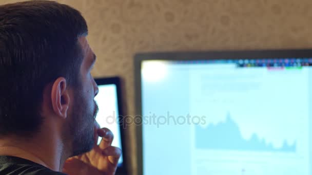 Молодой красивый мужчина с бородой хипстер работает на настольном компьютере дома или в офисе — стоковое видео