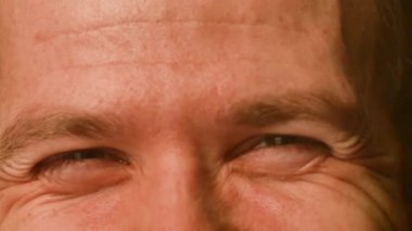 Genç bir beyaz erkek yakın çekim çekim gözleri. winks ve gülüyor, görünür kırışıklıkları