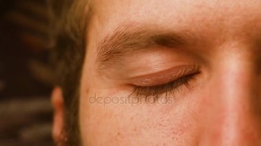 Kıvırcık saç planı olan genç bir beyaz adam gözlerini kapa. adam gülümseyerek gelen görünür yüz kırışıklıkları gülümsüyor