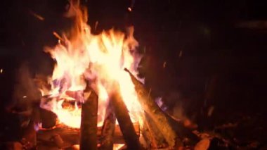 Yangın yeri alevleri günlükleri smoldering ve kar yakın çekim shot düşen şenlik ateşi gece kıvılcım yaktı