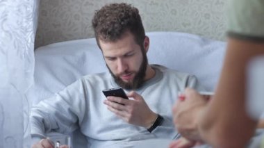 İki fiends oturuyorsun ve canlı sohbet, genç adam kahve göstermek bir şey üstünde belgili tanımlık perde smartphone birbirlerine içme