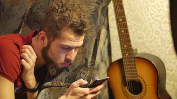 Een blanke jonge brunette krullend-bebaarde man maakt gebruik van de telefoon close-up handen met behulp van de mobiele telefoon touchscreen — Stockvideo