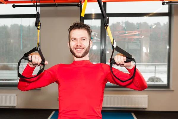 Crossfit instructor at the gym doing Excersise. Fitness man workout on the rings. Fitness man in the gym. Fitness style. Workout on rings. Sport and fitness. Crossfit workout