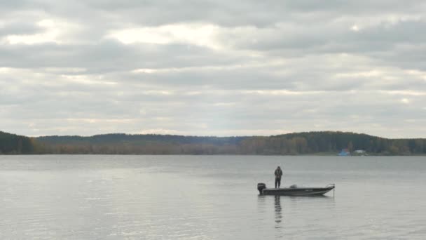 Pêcheur tire un poisson accroché sur le bateau au lac. Pêcheur dans le bateau de pêche au lac — Video