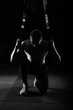Bir genç yakışıklı cesur kıvırcık sakallı kaslı adam sakallı toplam direnç egzersizleri fitness trx askıları spor salonu düşük anahtar çalışma dışarı yapar.