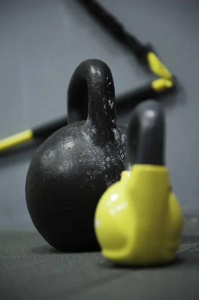 Diferentes tamanhos de pesos kettlebells deitado no chão ginásio. Equipamento comumente usado para treinamento crossfit no clube de fitness — Fotografia de Stock