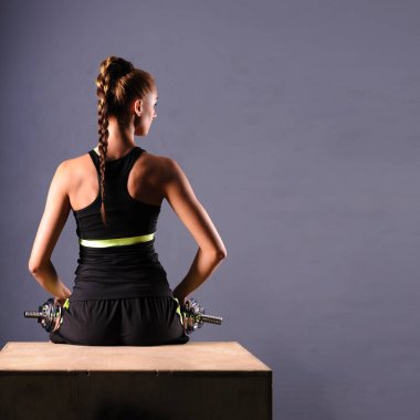 Uygun genç kadının omuz yapması dumbbells ile izole ongray arka plan yükseltir.