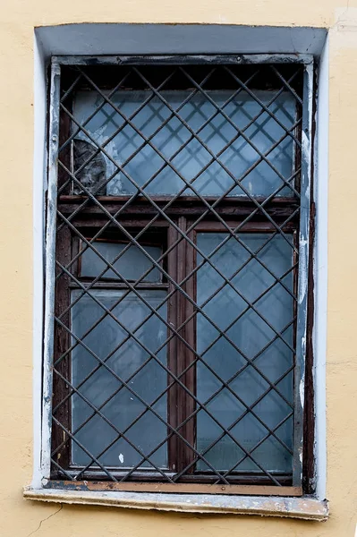 Vieja ventana con una rejilla oxidada en una vieja pared con ladrillos —  Fotos de Stock