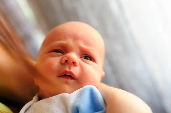 Cute baby girl makes a funny upset face on mothers hand — Stock Photo, Image