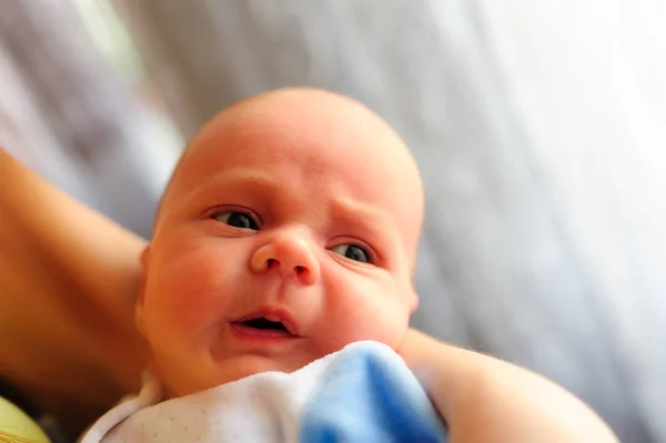 Cute baby girl makes a funny upset face on mothers hand — Stock Photo, Image