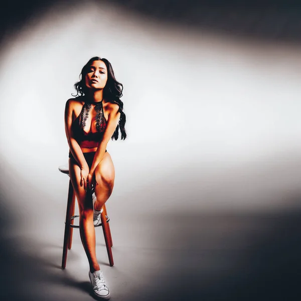 tüm vücut çekim moda moda stil genç seksi güzel Asyalı kadın sandalyede oturan kırmızı tulum içinde portresi