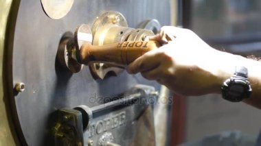 Kahve roastering. Taze kavrulmuş kahve boşaltma ve kavrulmuş kahve karıştırma. Roastering süreci. Yeşil ve kavrulmuş fasulye. Barista. Kafe
