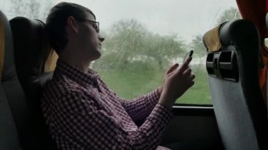 Uzun bir yolculukta otobüsün yanındaki işe giderken e-postalarını kontrol eden genç bir adam. Cep telefonu kullanımının yakın plan görüntüsü.