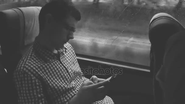 Ung manusing en mobiltelefon kontroll e-post på sin pendla till ett jobb med bussen på en lång resa. — Stockvideo