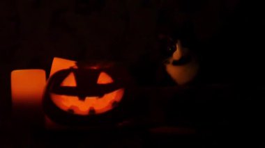 Oyma Halloween balkabağı ışıklar içinde alev yanan mumlar ile siyah bir arka plan ile kapatın. Slowmotion