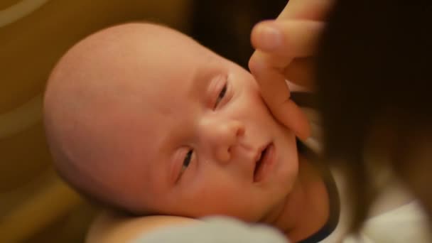 La jeune mère tient un bébé endormi dans ses bras et caresse doucement son visage. Maman s'occupe du bébé. Le concept de bien-être familial, d'amour et de tranquillité . — Video