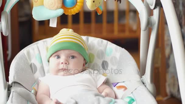 Fröhliche kleine niedliche Baby-Boy-Schaukel in elektrischer Schaukel im Wohnzimmer. — Stockvideo